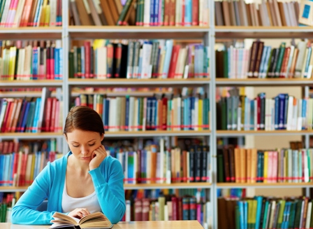 Bild von einem lesenden Mädchen in einer Bibliothek